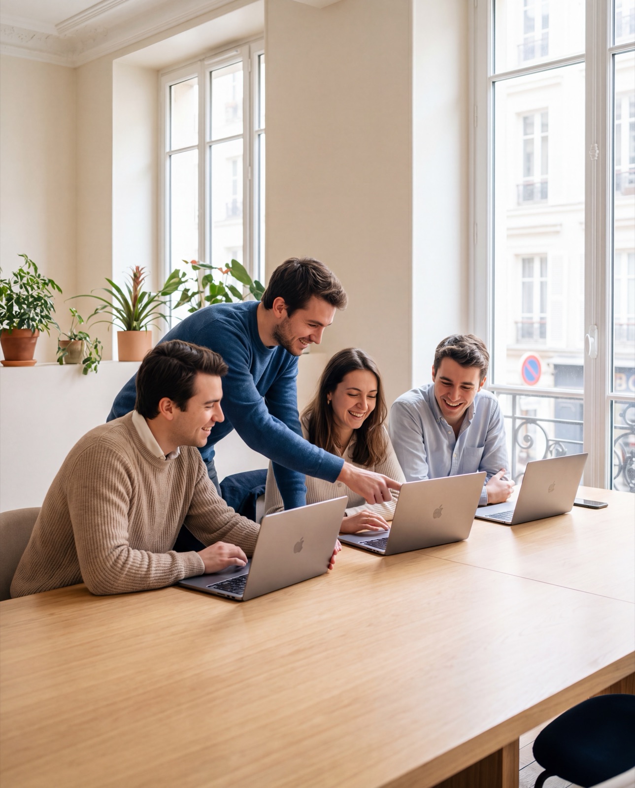 Quatre jeunes développeurs travaillent ensemble autour d'une table dans un bureau lumineux